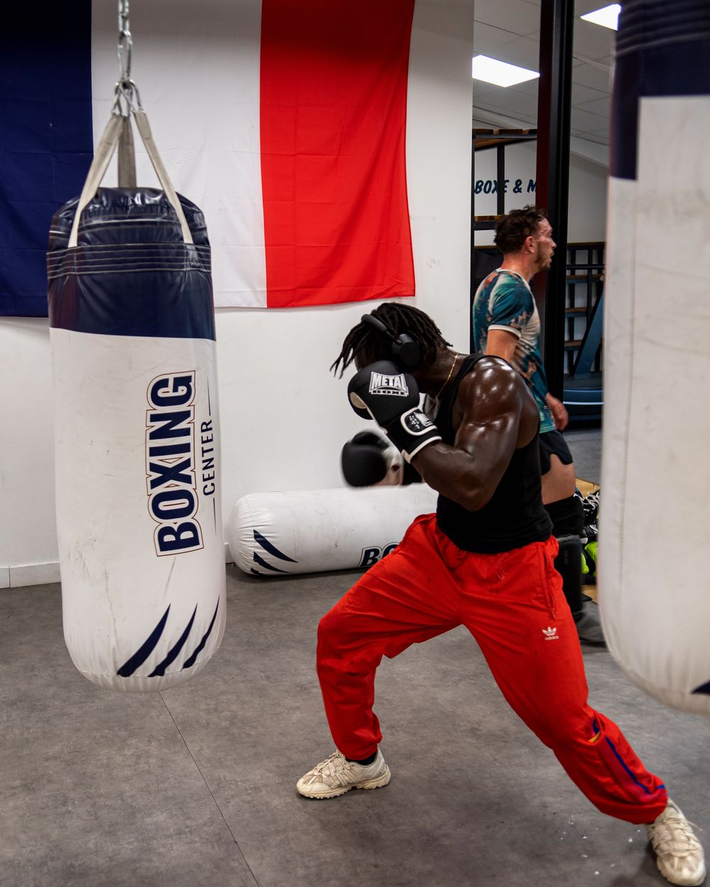 Boxeur casqué au sac de frappe Boxing Center, drapeau français au mur
