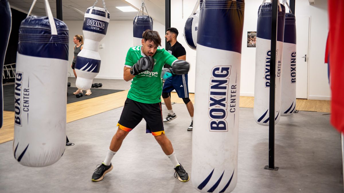 Boxeur en garde entre les sacs de frappe Boxing Center, dans l’espace boxe