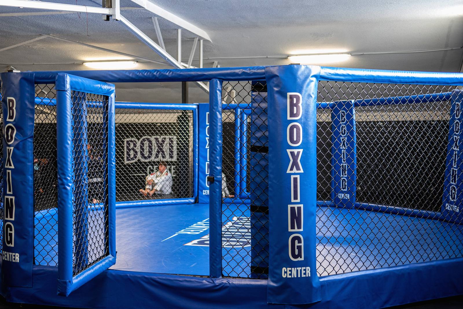 La cage MMA du Boxing Center Toulouse États-Unis, vide, les poteaux marqués Boxing Center