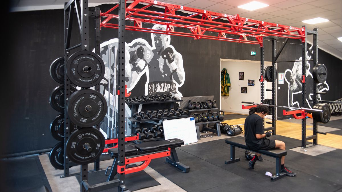 Espace de préparation physique : rig rouge, disques et bancs de musculation
